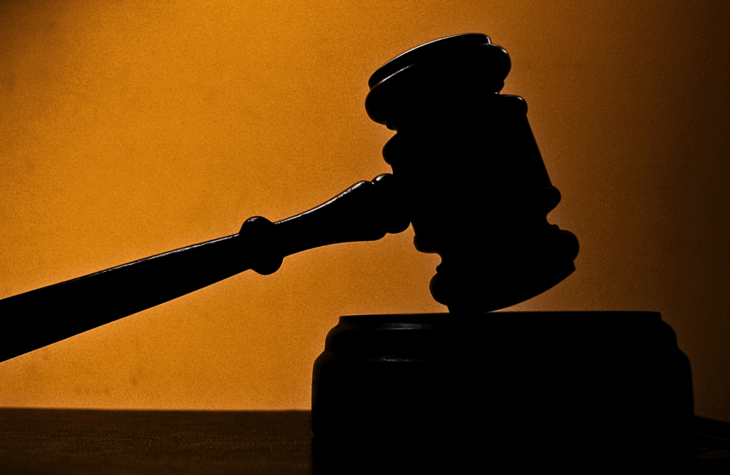 Dramatic silhouette of a gavel raised over a block, suggesting decisive legal authorit
